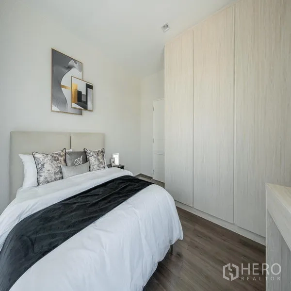 Detached House for rent in Samut Prakan - Secondary bedroom with fitted wardrobe, wood flooring and wall art.