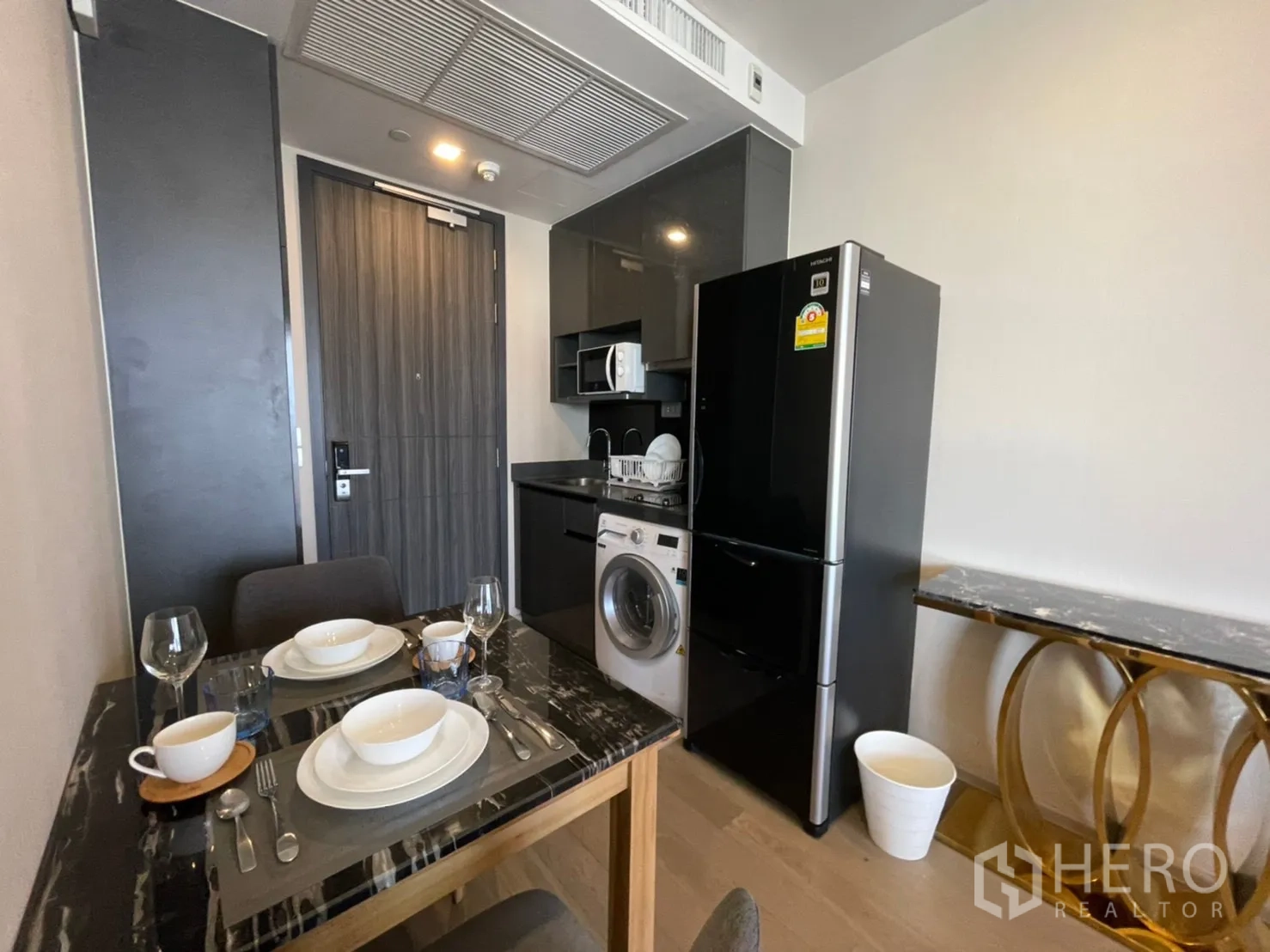 คอนโด for rent in Watthana, Bangkok - มุมครัวย่อมพร้อมตู้เย็นสีดำ ไมโครเวฟ เครื่องซักผ้า และโต๊ะทานอาหาร