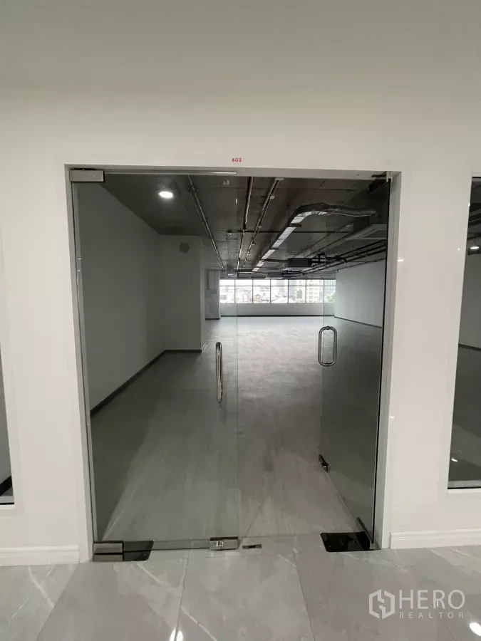Office Space for rent in Bang Rak, Bangkok - Glass double doors opening to a bright open‑plan office with grey flooring and a wide window wall.