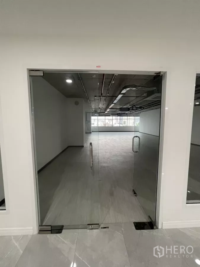 Office Space for rent in Bang Rak, Bangkok - Glass double doors opening to a bright open‑plan office with grey flooring and a wide window wall.