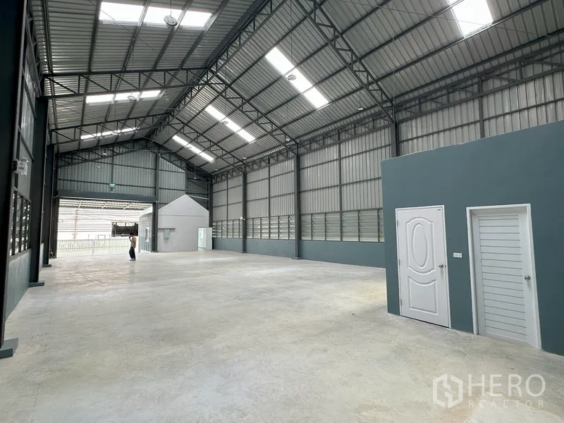 Factory for rent in Khlong Luang, Pathum Thani - Interior aisle with skylit roof and white service doors along the side wall.