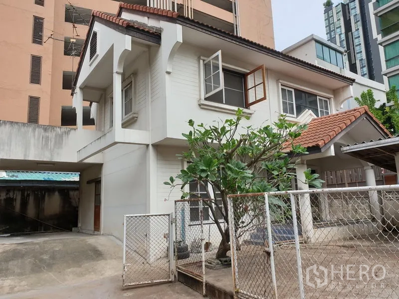 独立式住宅 出租或出售在Watthana, Bangkok - 两层独栋住宅，红瓦屋顶，带大门与车棚，前院有成树。