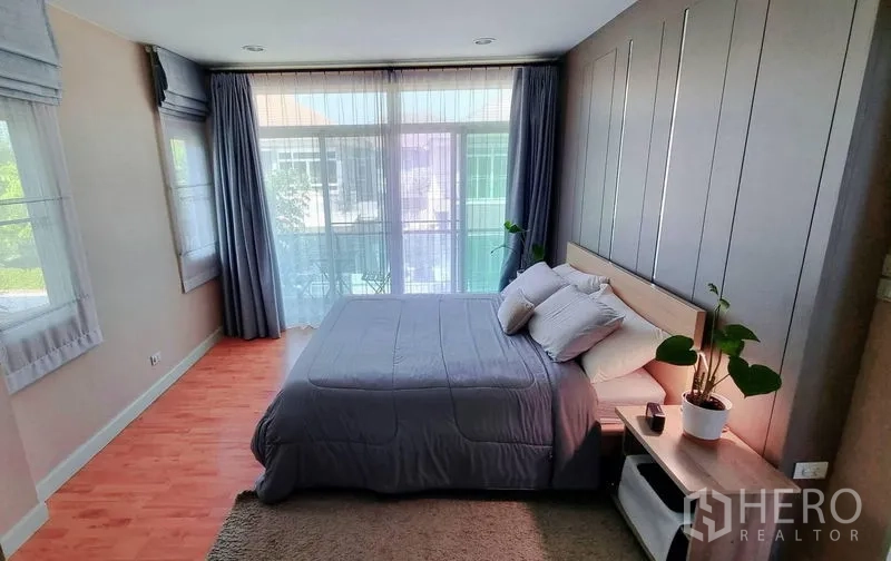 Detached House for rent or sale in Saphan Sung, Bangkok - Sunlit master bedroom with king bed, feature wall and balcony glazing.