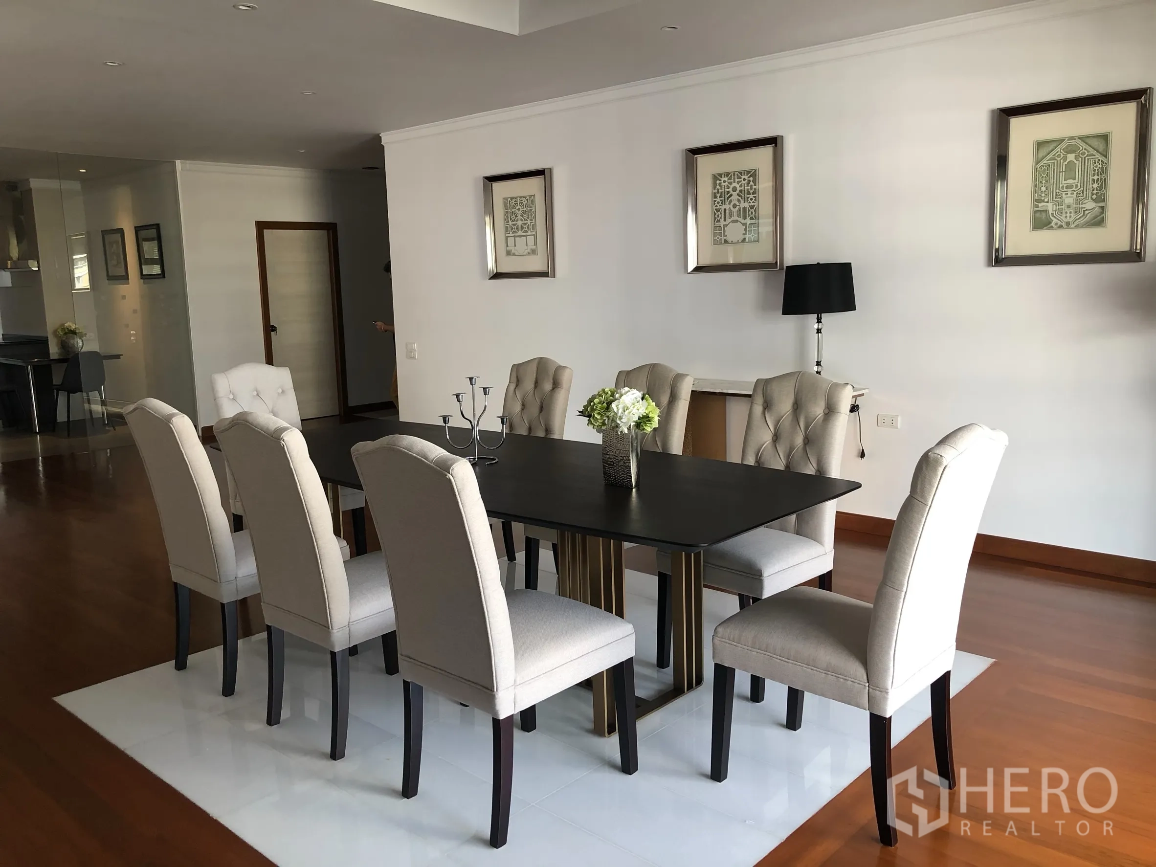 Condominium for rent in Bangkok - Formal dining room with eight upholstered chairs and a black table on wood floors.