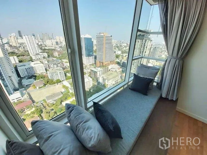 Condominium for rent in Watthana, Bangkok - High‑floor window seat with cushions overlooking the Bangkok skyline.