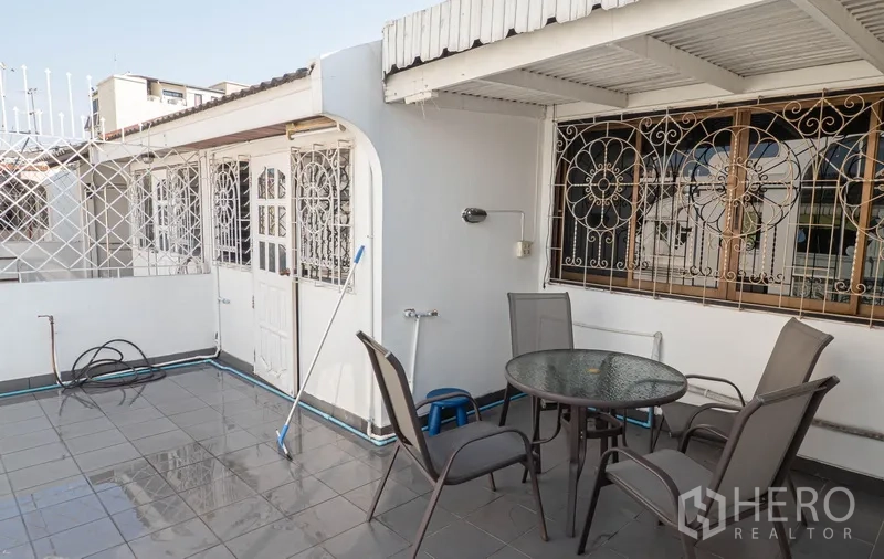 Townhouse for rent in Watthana, Bangkok - Rooftop terrace with outdoor table and chairs under partial shade.