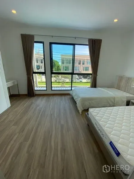 Townhouse for rent in Bang Kapi, Bangkok - Bright bedroom with twin beds and floor-to-ceiling windows overlooking the neighborhood.