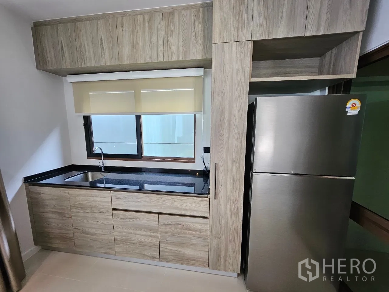 Detached House for rent in Bang Kapi, Bangkok - Modern kitchenette with black countertop, sink and stainless refrigerator.
