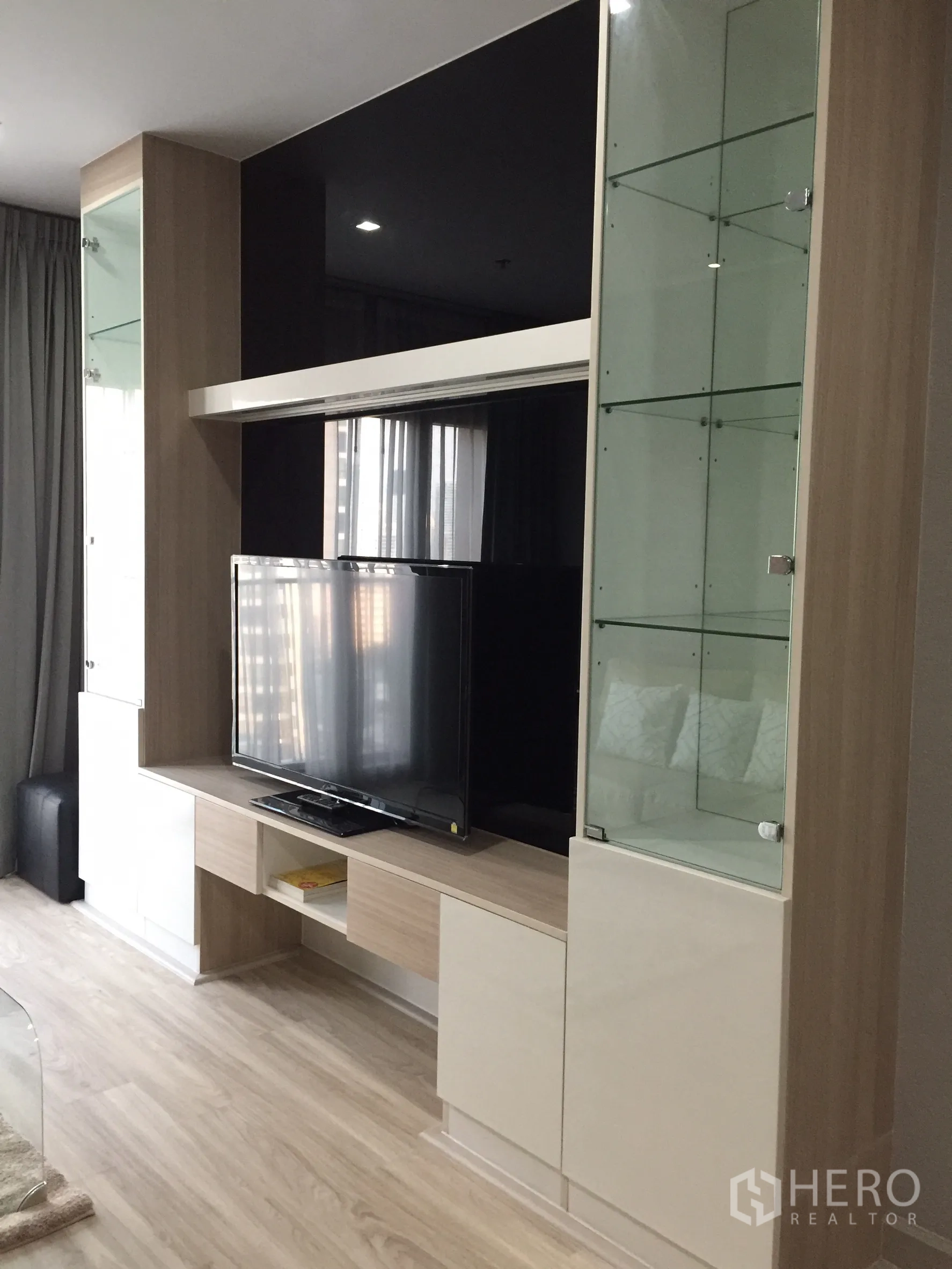 Condominium for rent or sale in Bangkok - Living room media unit with glass display cabinets and flat-screen TV.