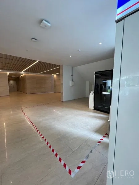 Retail Space for rent - Open retail bay in a clean lobby with recessed lighting and polished stone flooring.