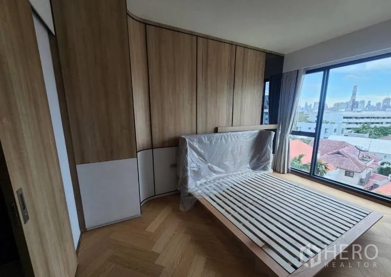 公寓 出租或出售在Phaya Thai, Bangkok - 转角卧室，落地窗与木质定制衣柜，享城市景观。