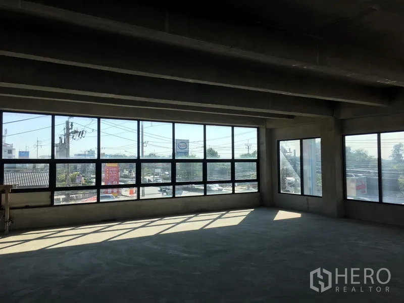 Home Office for rent in Lat Krabang, Bangkok - Open‑plan office floor with expansive corner windows providing abundant natural light and views over the nearby roadway.