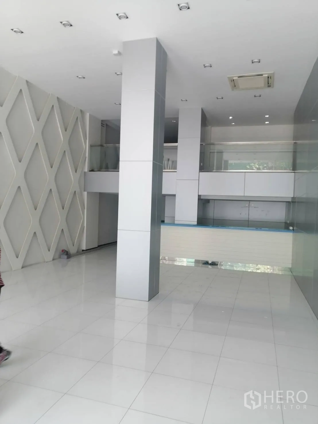 零售空间 出租在Watthana, Bangkok - 挑高大堂，白色地砖、立柱与玻璃栏杆的夹层。