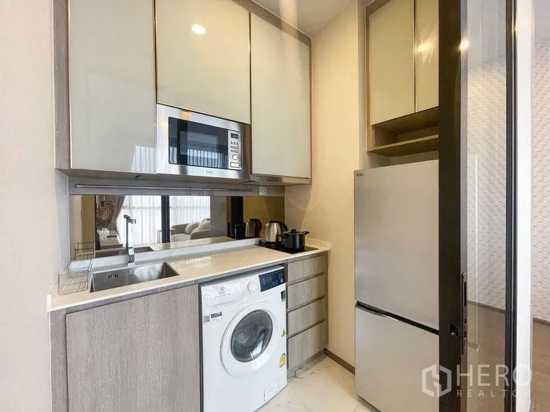 公寓 出租在Ratchathewi, Bangkok - 紧凑厨房配微波炉、水槽、炉台、洗衣机与上方橱柜。