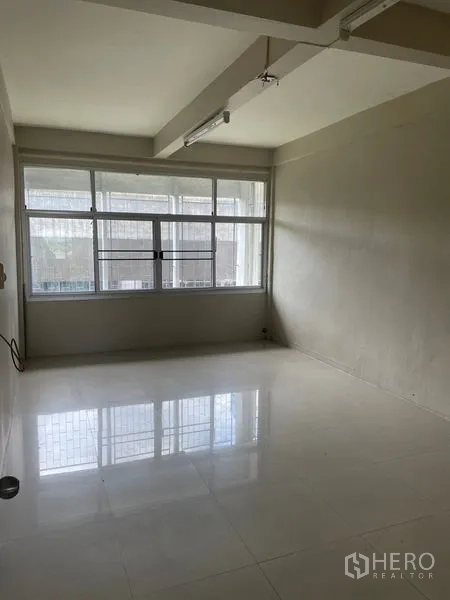 Shophouse for rent in Phra Khanong, Bangkok - Clean office-style room with wide window and polished tile floor.