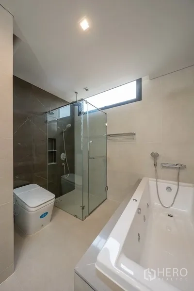 Detached House for rent or sale in Yan Nawa, Bangkok - Contemporary bathroom with glass shower, bathtub and a daylight window.