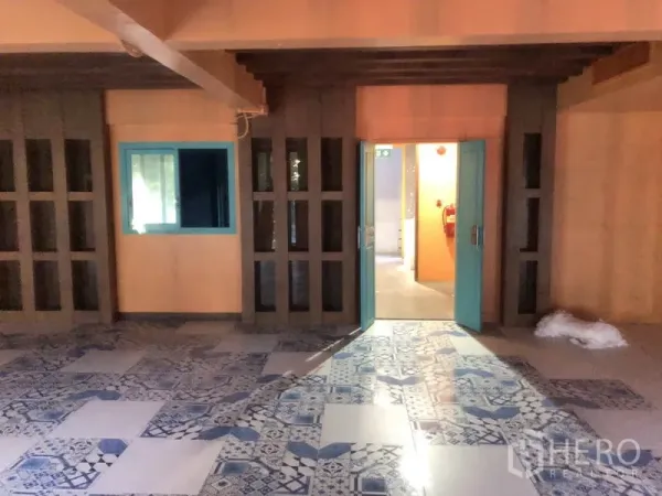 Retail Space for rent in Khlong Toei, Bangkok - Teal double doors and windowed partitions opening to a corridor, with decorative patterned floor tiles inside a retail unit.
