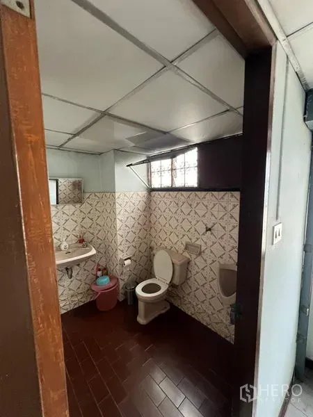 Shophouse for sale - Bathroom with tiled walls, toilet, sink and a small glass-block window.