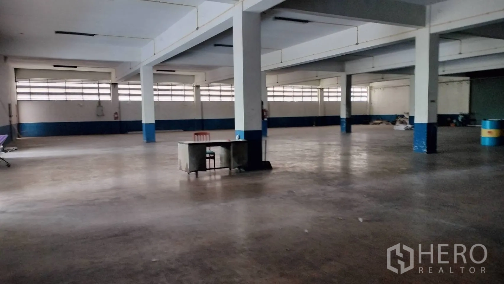 โรงงาน for rent in Lat Krabang, Bangkok - พื้นที่ภายในกว้าง มีเสาและไฟฟลูออเรสเซนต์ พร้อมโต๊ะทำงานตรงกลาง.