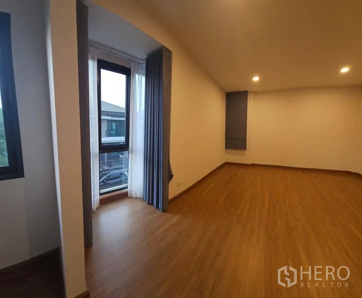 Detached House for rent in Saphan Sung, Bangkok - Large master bedroom with bay window nook, curtains and warm wood-look flooring.