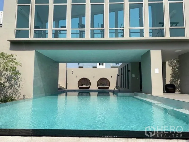 Townhouse for rent in Bang Na, Bangkok - Residents’ swimming pool with shaded area beneath a glass-walled pavilion.