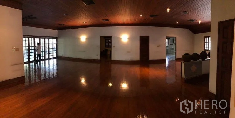 Detached House for sale in Bang Na, Bangkok - Expansive living room with polished wooden floors, wood ceiling and a wall of French glass doors.