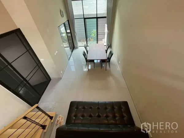 联排别墅 出租在Suan Luang, Bangkok - 双层挑高客餐厅，落地窗与亮面地砖，曼谷素安鲁昂现代联排别墅室内。