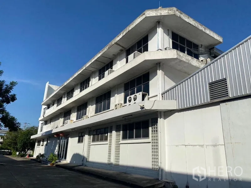 Warehouse for rent in Mueang Samut Prakan, Samut Prakan - Attached multi-storey office building with rows of windows next to the warehouse.