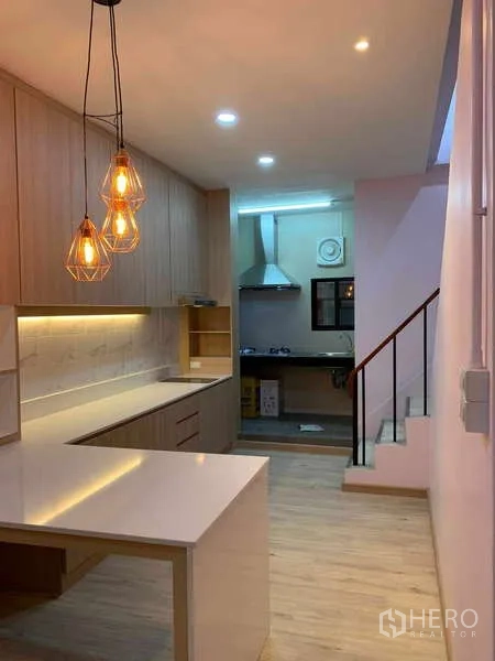 Townhouse for rent - Kitchen walkway toward a separate wet kitchen with warm pendant lighting and ample storage.