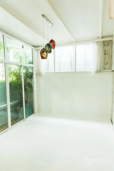 联排别墅 出售在Wang Thonglang, Bangkok - 封闭式白色日光房，彩色吊灯与花园景。