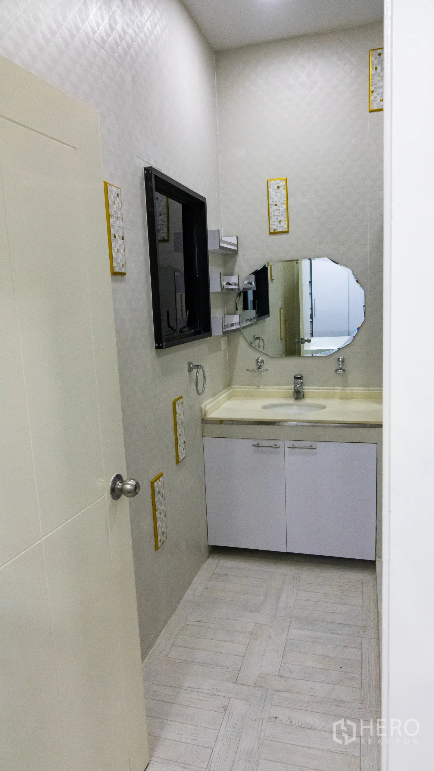 Condominium for rent or sale in Khlong Toei, Bangkok - Vanity area with cream countertop, storage cabinets and an octagonal mirror.