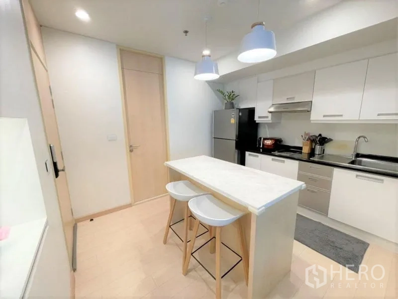 Condominium for rent or sale - Modern white kitchen with an island breakfast bar, pendant lights and stainless appliances.