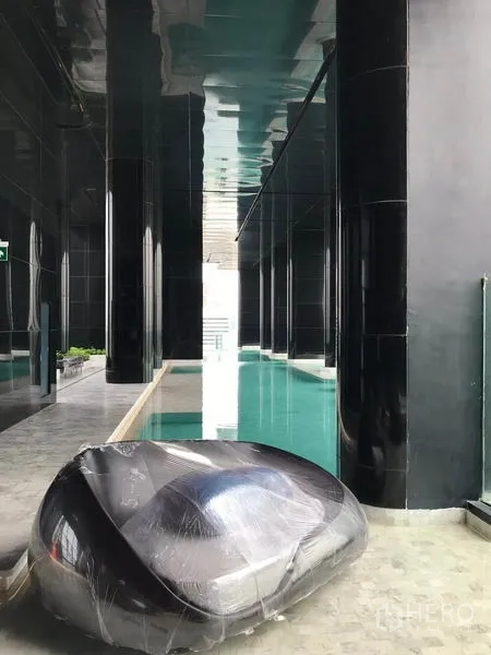 Condominium for rent in Watthana, Bangkok - Sleek indoor lap pool with black columns and a contemporary lounge seat by the water.