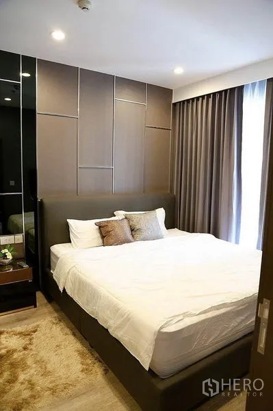 公寓 出租在Huai Khwang, Bangkok - 采光充足的卧室，绒面地毯、软包床头与全遮光窗帘。