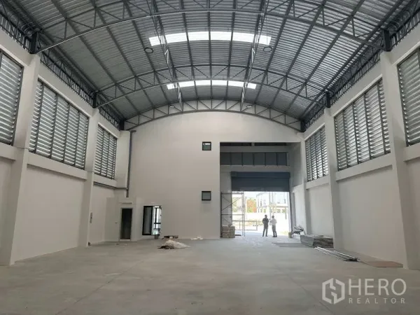 工厂 出售在Lam Luk Ka, Pathum Thani - 高挑仓库内部，钢结构屋顶、百叶通风窗与加宽卷帘门。
