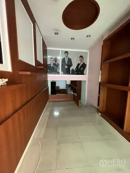 Shophouse for rent in Khlong Toei, Bangkok - Ground-floor space with tiled flooring, recessed lights, and built-in wooden shelving.