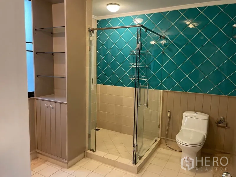 Condominium for rent in Watthana, Bangkok - Bathroom with glass shower enclosure, teal feature tile wall and open shelving.