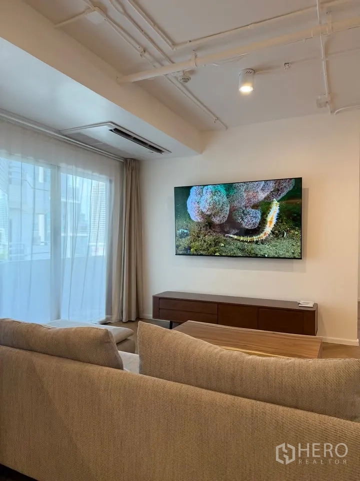 公寓 for rent in Watthana, Bangkok - 客厅墙挂电视、矮柜与纱帘窗饰。