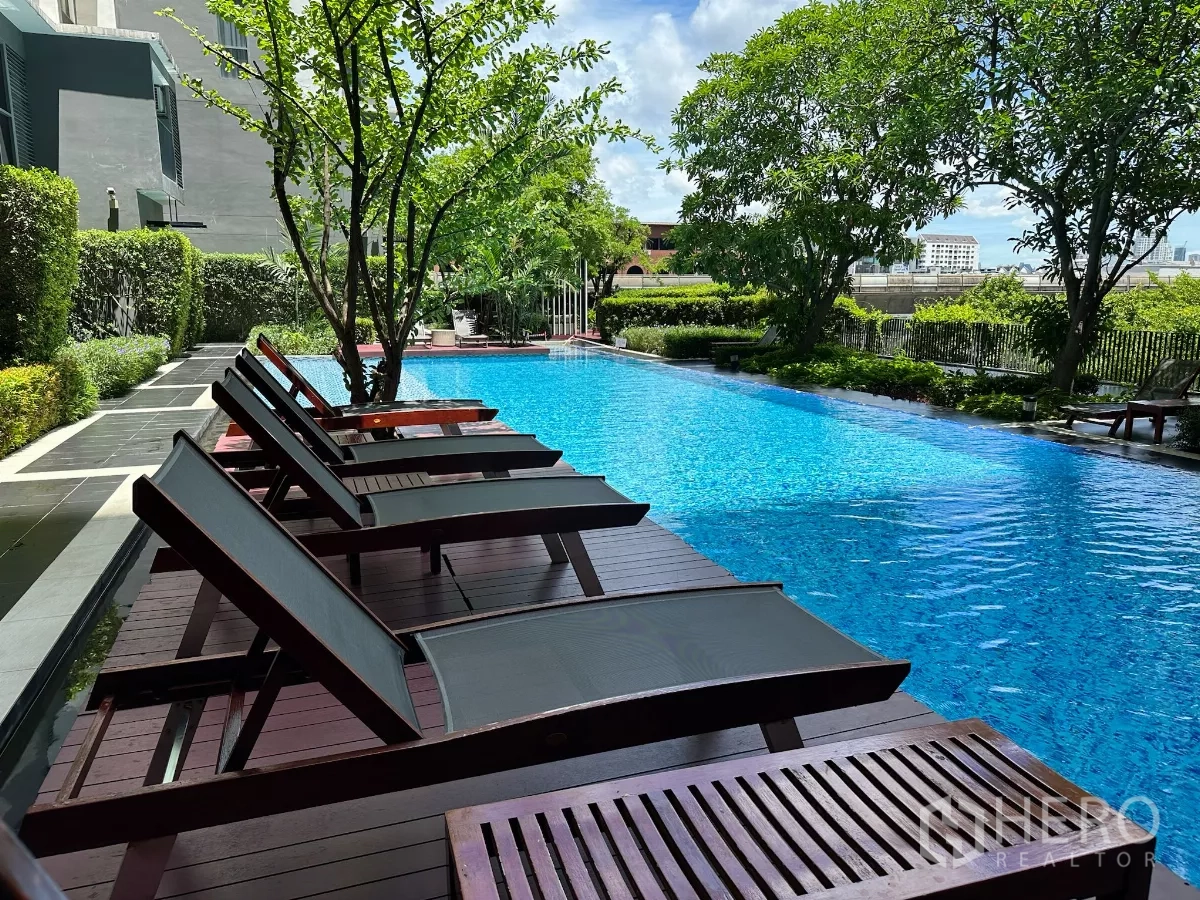 公寓 出售在Phra Khanong, Bangkok - 室外泳池与躺椅，绿意环绕的休闲空间。