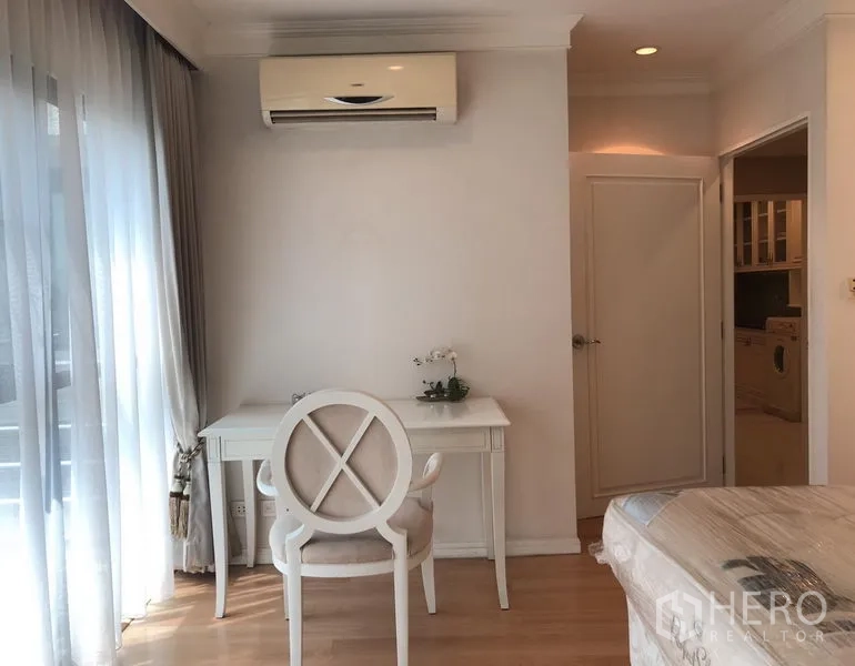 Condominium for rent or sale in Sathon, Bangkok - Bright bedroom corner with writing desk, sheer curtains and wooden flooring.