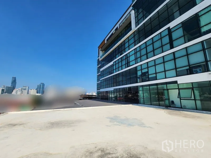 Retail Space for rent in Bang Rak, Bangkok - Modern glass-façade building beside rooftop with skyline beyond.