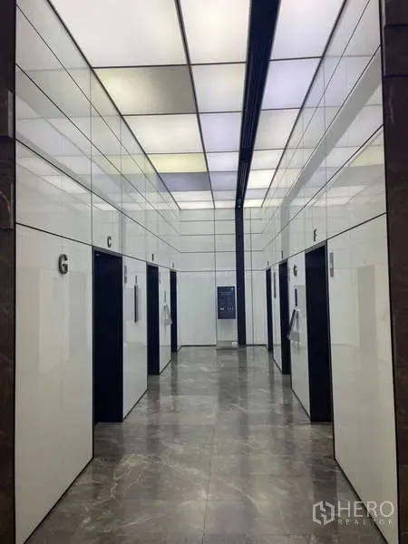 Office Space for rent in Bang Kapi, Bangkok - Sleek elevator lobby with multiple lifts, glossy white wall panels and marble floors.