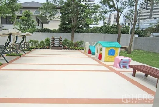 Apartment for rent in Khlong Toei, Bangkok - Outdoor area with swings, children’s playhouse and benches in a landscaped courtyard