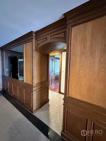 Condominium for rent in Bangkok - Wood-paneled hallway with arched doorway leading to bedrooms.