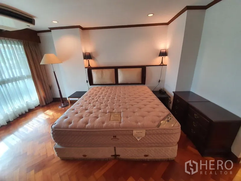 Condominium for rent in Pathum Wan, Bangkok - Cozy bedroom with king bed, bedside lamps, and floor-to-ceiling curtains.