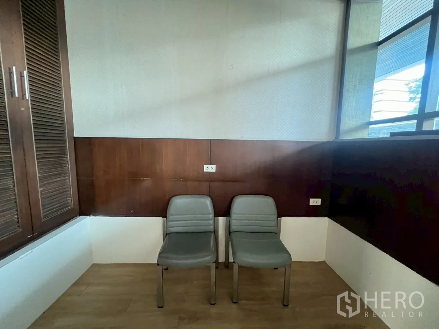 Retail Space for rent - Small corner with wood wall paneling, storage and two chairs near the window.
