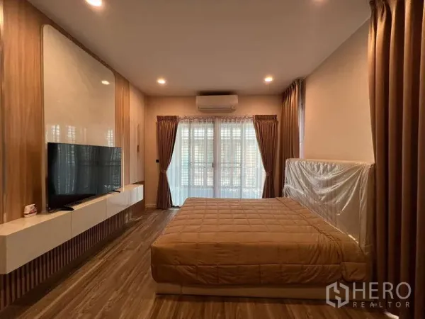 Detached House for rent in Bang Kapi, Bangkok - Spacious master bedroom with wall-mounted TV, built-in console and balcony doors.