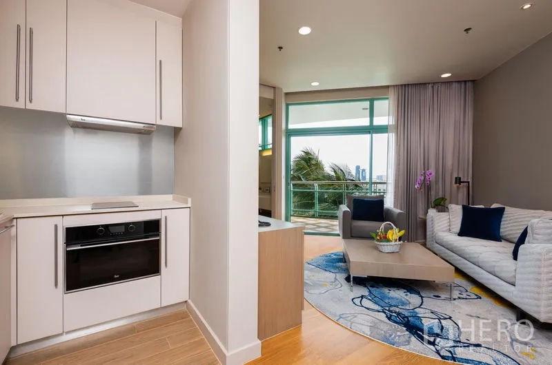 Condominium for rent in Bang Kho Laem, Bangkok - Open kitchenette beside a bright living room with full-height windows and city and palm views.
