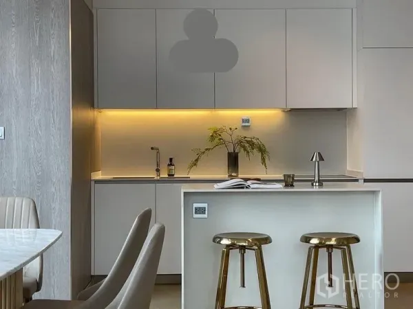 Condominium for rent in Watthana, Bangkok - Modern kitchen with white cabinetry, under-cabinet lighting, and a marble island with gold bar stools.