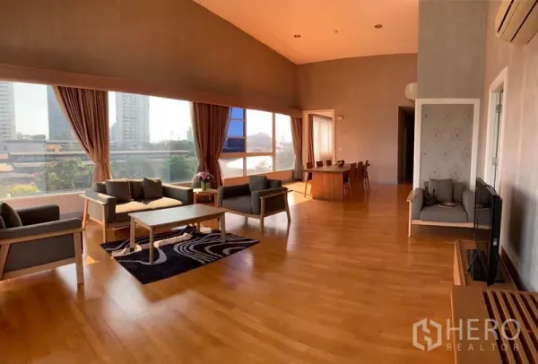Condominium for sale in Khlong San, Bangkok - Open-plan lounge and dining area with large windows, city skyline outlook and hardwood flooring.